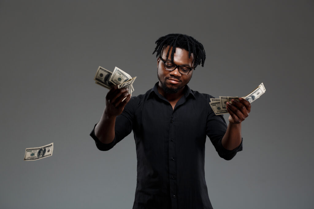 Young successful african businessman throwing money